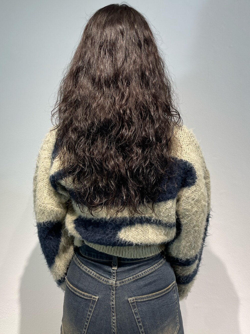 ブルー系のニット/セーター、ブルー系のデニムパンツ、シルバー系のハンドバッグを着用したレディースの秋コーディネートの6枚目の写真