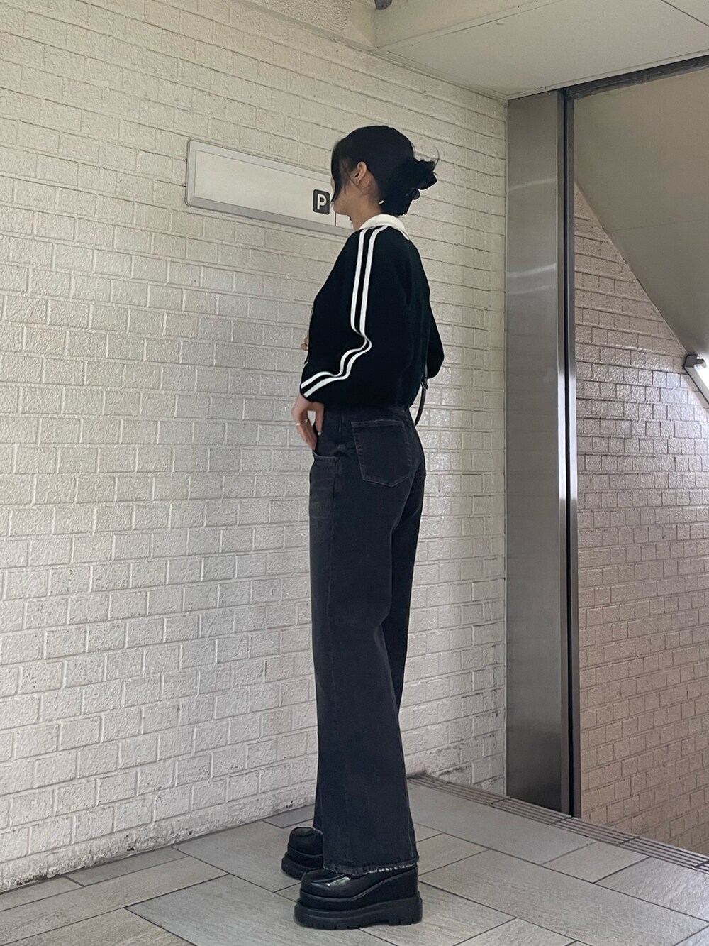 ブラック系のニット/セーター、ブラック系のハンドバッグ、ブラック系のデニムパンツを着用したレディースの冬コーディネートの2枚目の写真