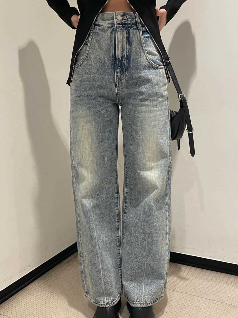 ブラック系のニット/セーター、ブルー系のデニムパンツ、ブラック系のハンドバッグを着用したレディースの冬コーディネートの7枚目の写真