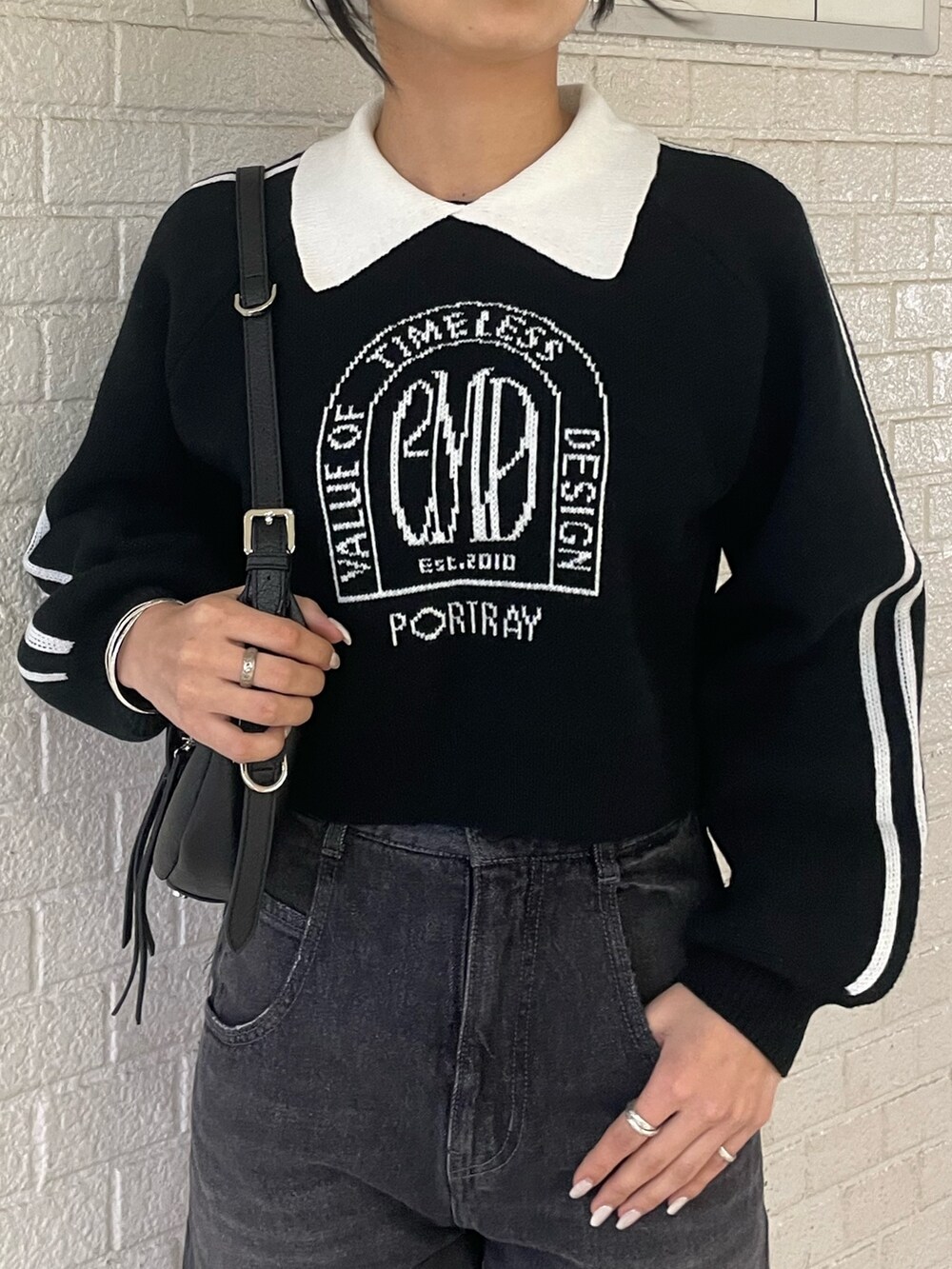 ブラック系のニット/セーター、ブラック系のハンドバッグ、ブラック系のデニムパンツを着用したレディースの冬コーディネートの4枚目の写真