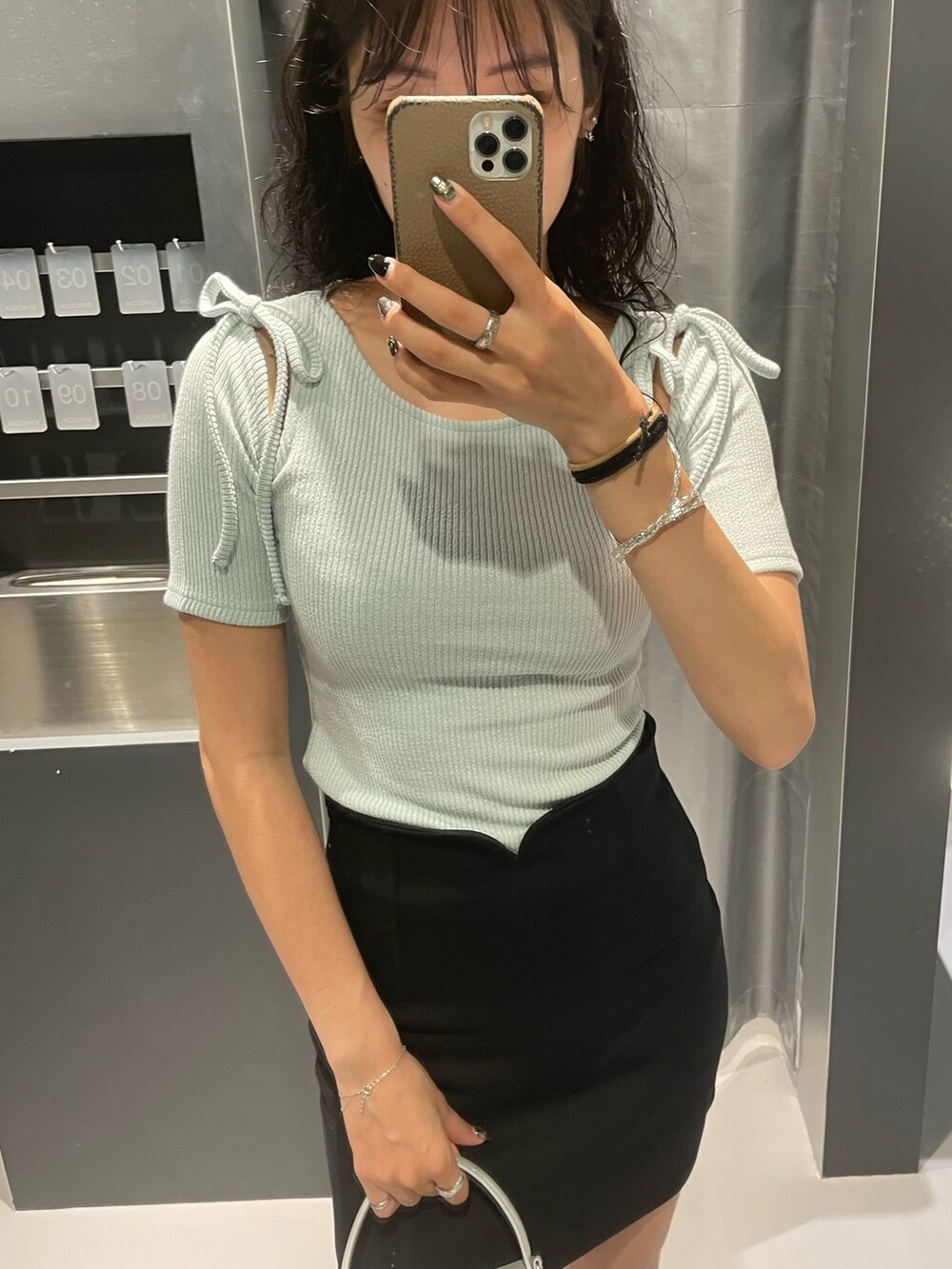 ブルー系のTシャツ/カットソー、ブラック系のスカート、シルバー系のハンドバッグを着用したレディースの夏コーディネートの4枚目の写真