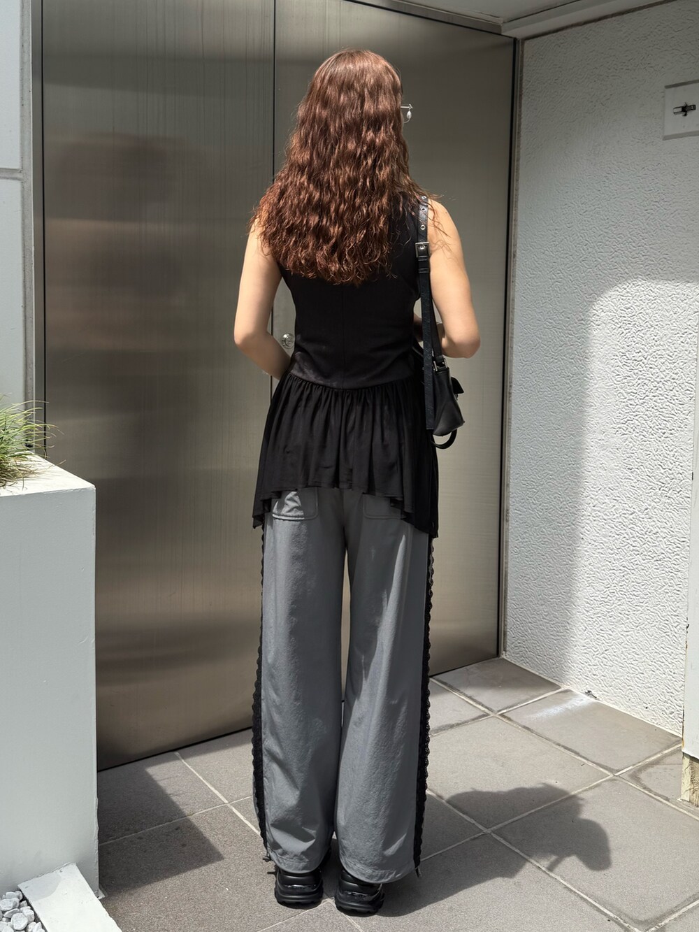 ブラック系のTシャツ/カットソー、ブラック系のハンドバッグ、グレー系のその他パンツを着用したレディースの夏コーディネートの3枚目の写真