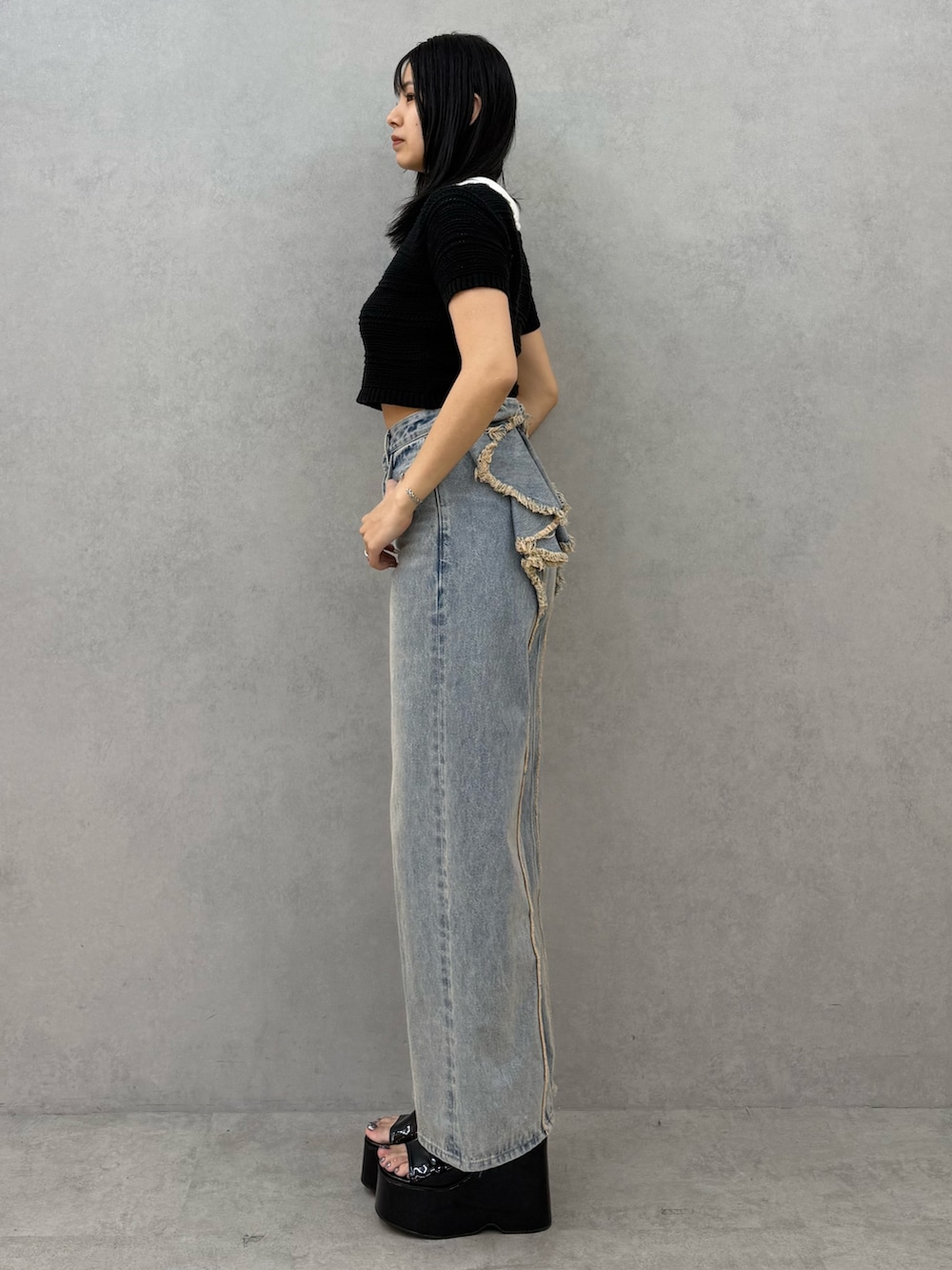 ブラック系のニット/セーター、ブルー系のデニムパンツ、ブラック系のサンダルを着用したレディースの春コーディネートの2枚目の写真