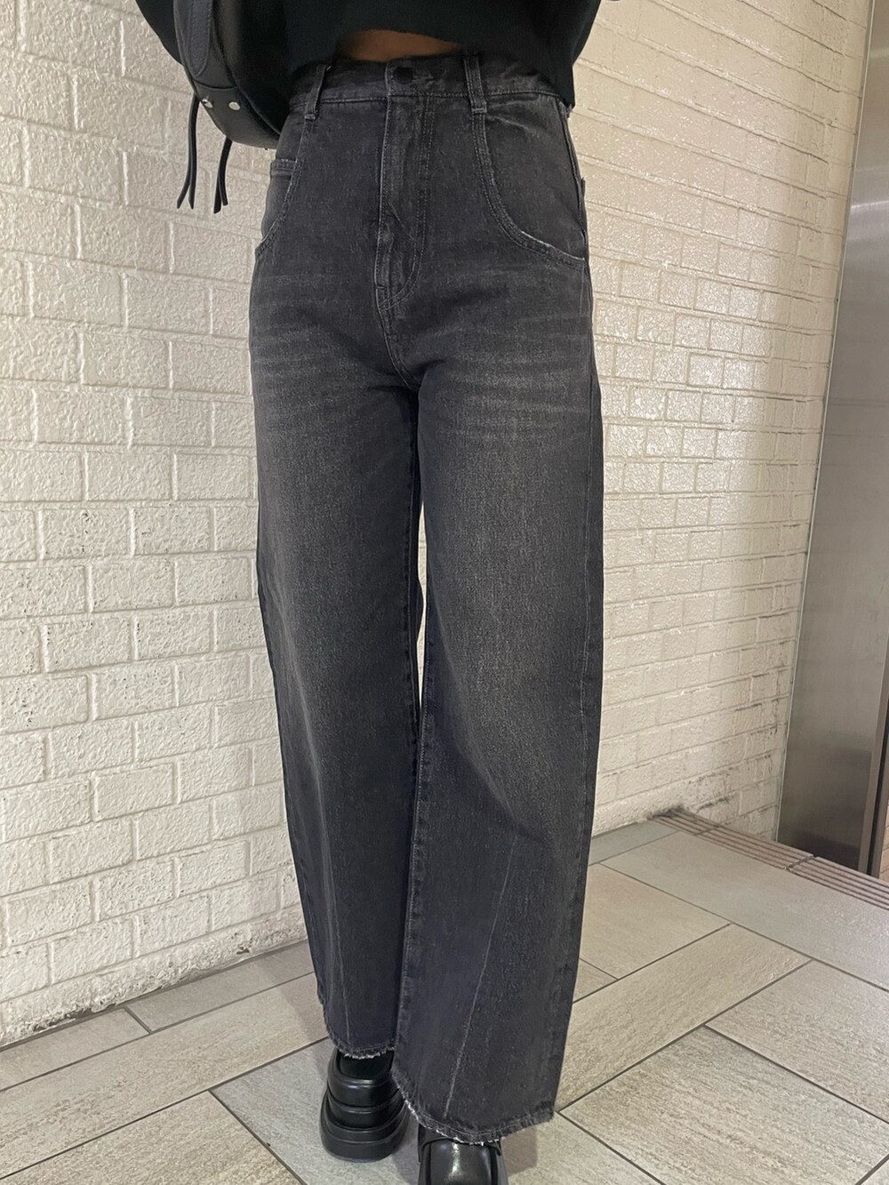 ブラック系のニット/セーター、ブラック系のハンドバッグ、ブラック系のデニムパンツを着用したレディースの冬コーディネートの7枚目の写真