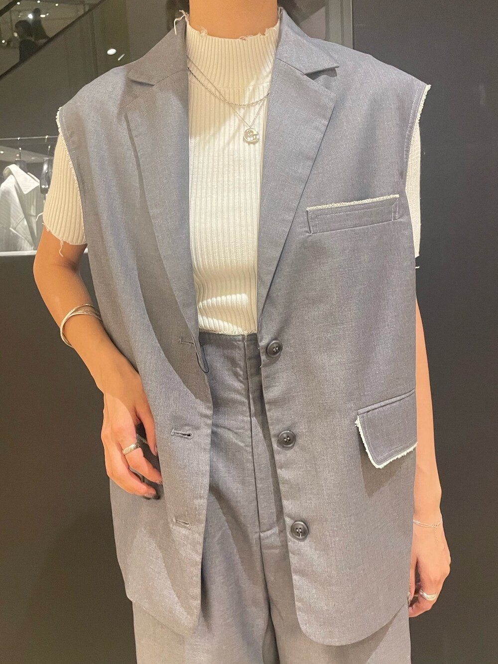 ホワイト系のニット/セーター、ホワイト系のハンドバッグ、グレー系のベストを着用したレディースの夏コーディネートの5枚目の写真