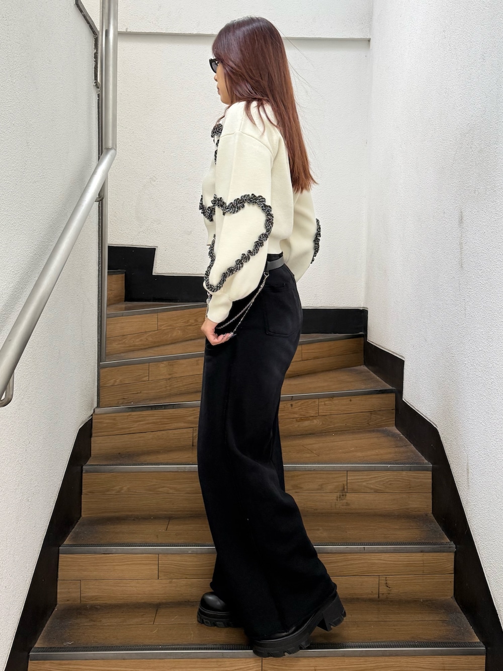 ホワイト系のニット/セーター、ブラック系のスウェットパンツ、ブラック系のブーツを着用したレディースの冬コーディネートの2枚目の写真