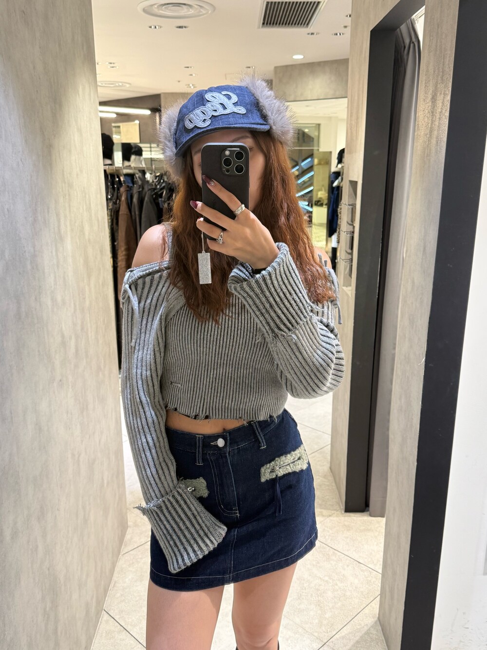 グレー系のニット/セーター、ブルー系のスカート、ブラック系のブーツを着用したレディースの秋コーディネートの4枚目の写真