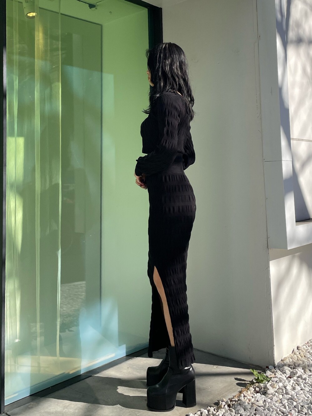 ブラック系のニット/セーター、ブラック系のスカート、ブラック系のブーツを着用したレディースの春コーディネートの2枚目の写真