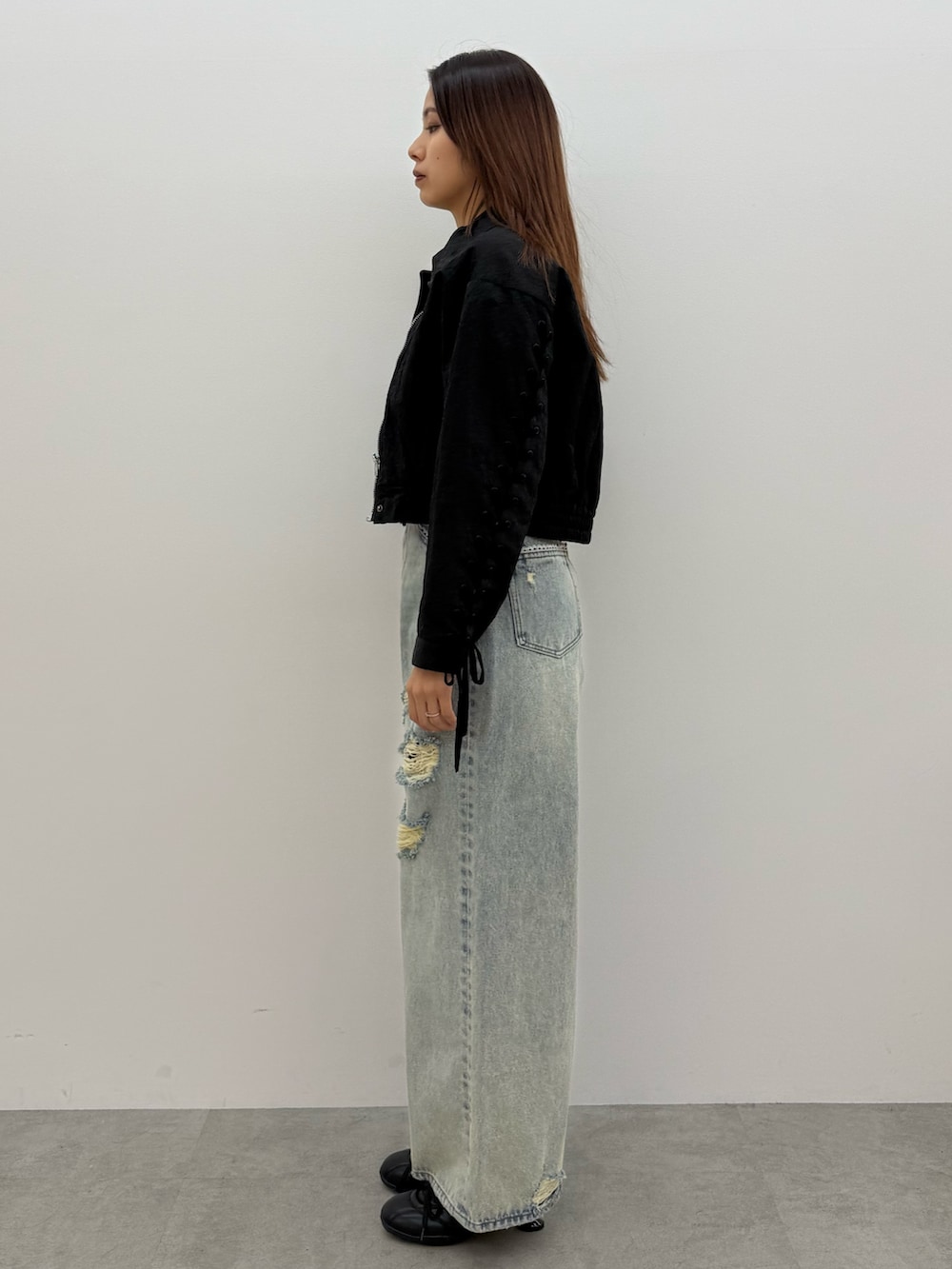 ブラック系のブルゾン、ホワイト系のTシャツ/カットソー、ブルー系のデニムパンツを着用したレディースの冬コーディネートの2枚目の写真