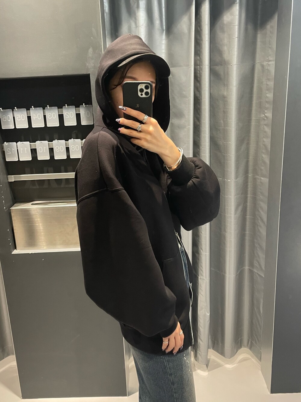 ブラック系のパーカー、ブルー系のデニムパンツ、ブラック系のブーツを着用したレディースの秋コーディネートの5枚目の写真