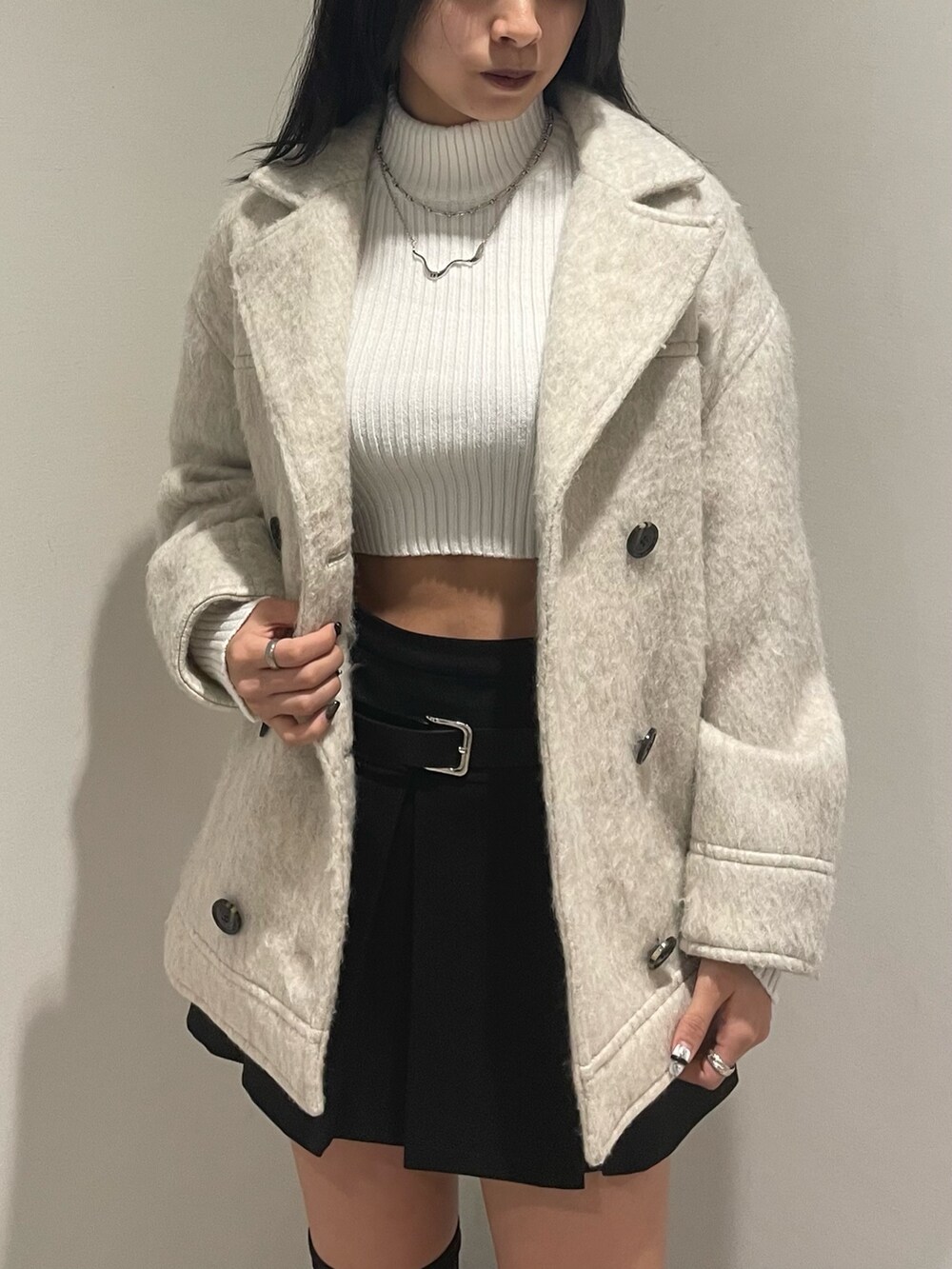 ホワイト系のニット/セーター、ホワイト系のピーコート、ブラック系のスカートを着用したレディースの冬コーディネートの4枚目の写真