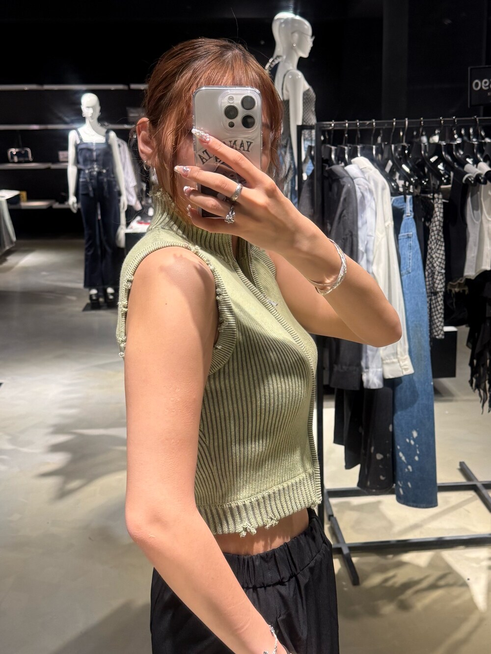 グリーン系のタンクトップ、ブルー系のデニムパンツ、ブラック系のハンドバッグを着用したレディースの夏コーディネートの5枚目の写真