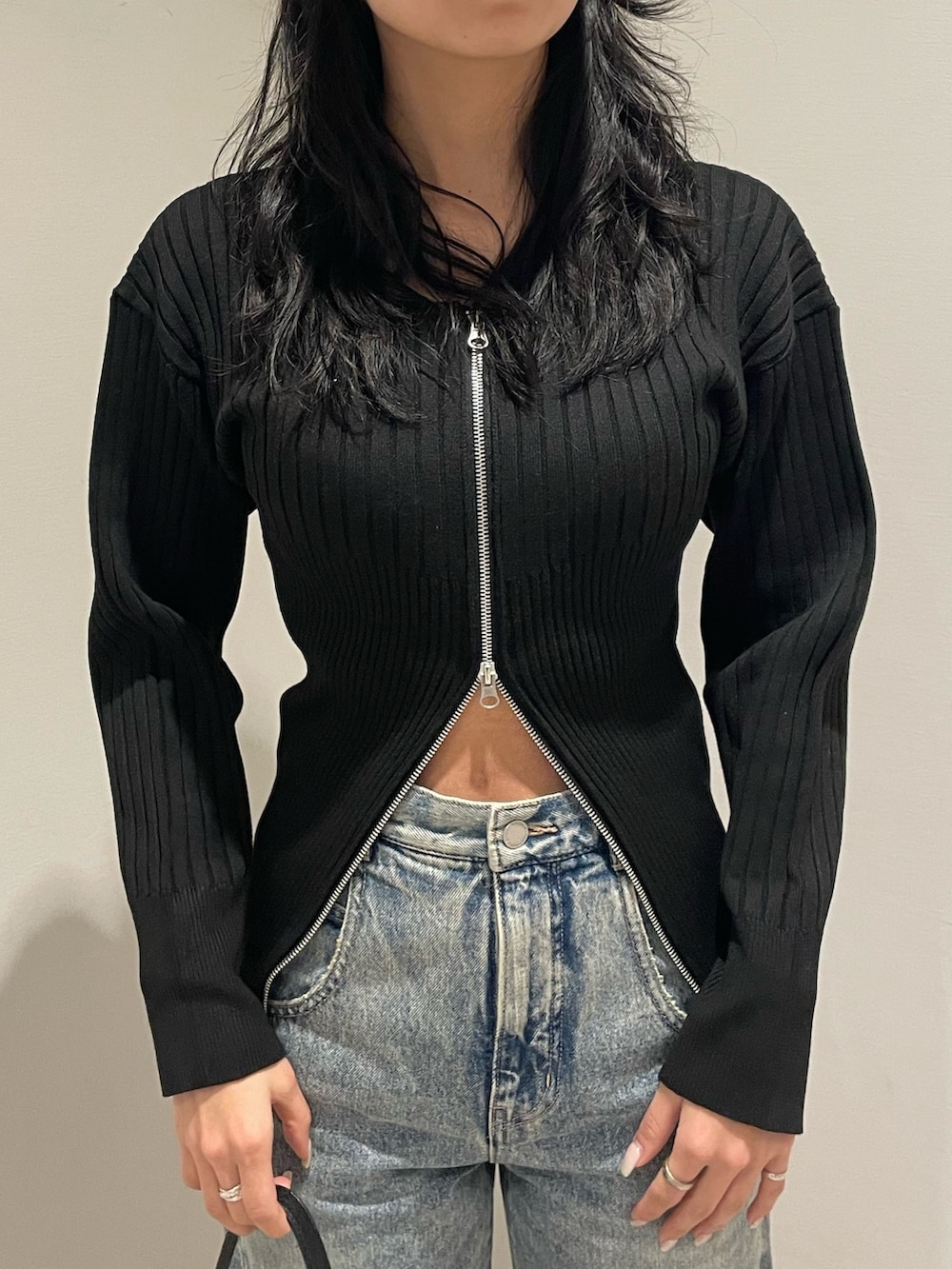 ブラック系のニット/セーター、ブルー系のデニムパンツ、ブラック系のハンドバッグを着用したレディースの冬コーディネートの4枚目の写真