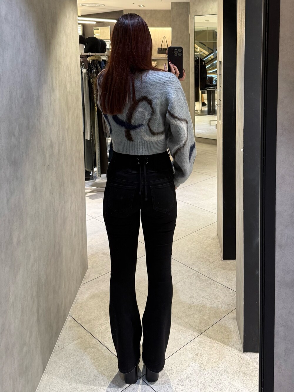 グレー系のニット/セーター、ブラック系のブーツ、ブラック系のデニムパンツを着用したレディースの秋コーディネートの3枚目の写真