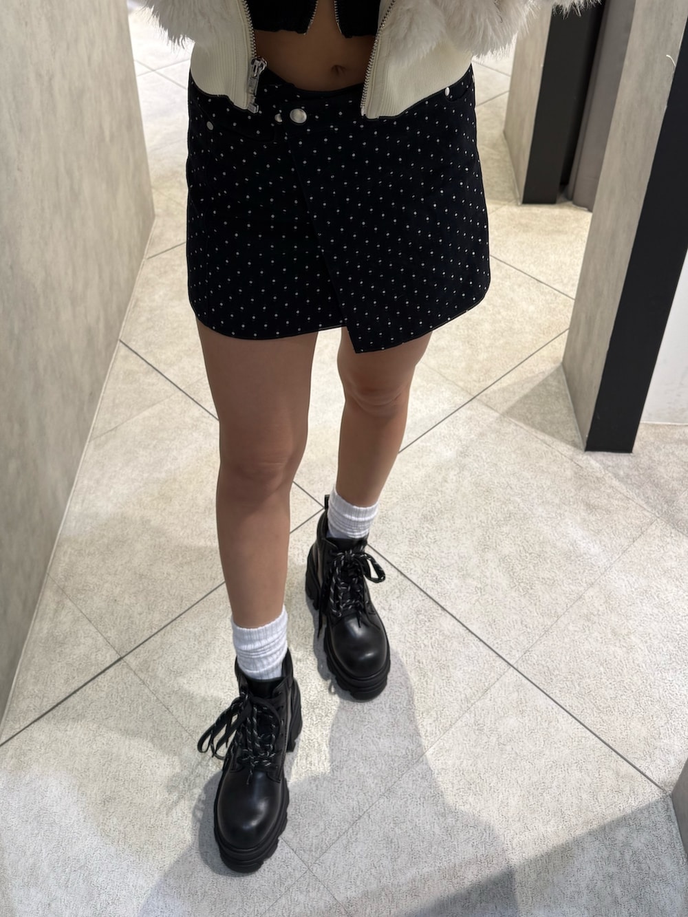 ホワイト系のブルゾン、ブラック系のニット/セーター、ブルー系のスカートを着用したレディースの秋コーディネートの6枚目の写真