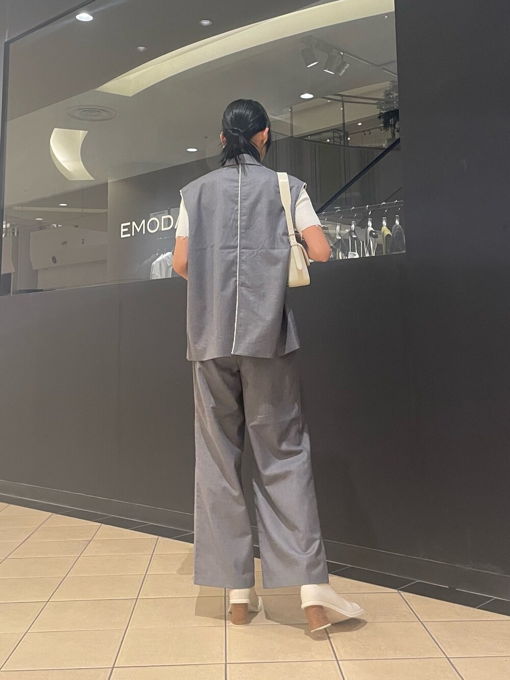 ホワイト系のニット/セーター、ホワイト系のハンドバッグ、グレー系のベストを着用したレディースの夏コーディネートの3枚目の写真