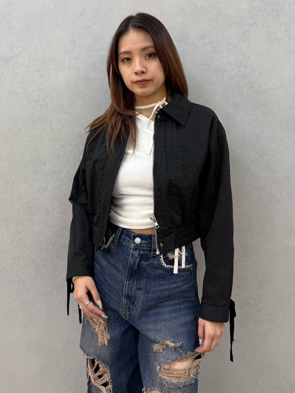 ブラック系のブルゾン、ホワイト系のニット/セーター、ブルー系のデニムパンツを着用したレディースの冬コーディネートの4枚目の写真