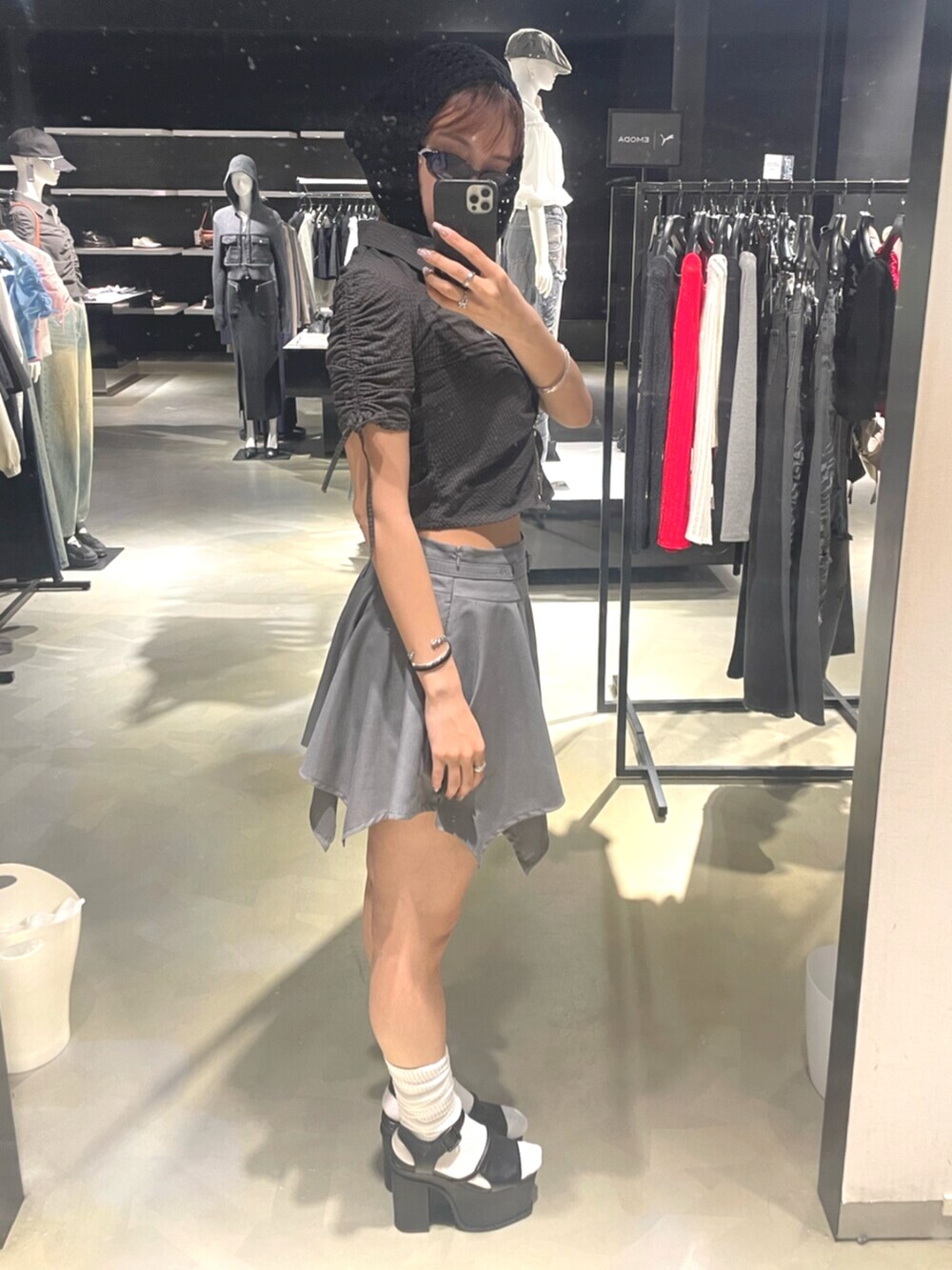 ブラック系のサンダル、グレー系のスカート、ブラック系のシャツ/ブラウスを着用したレディースの春コーディネートの2枚目の写真