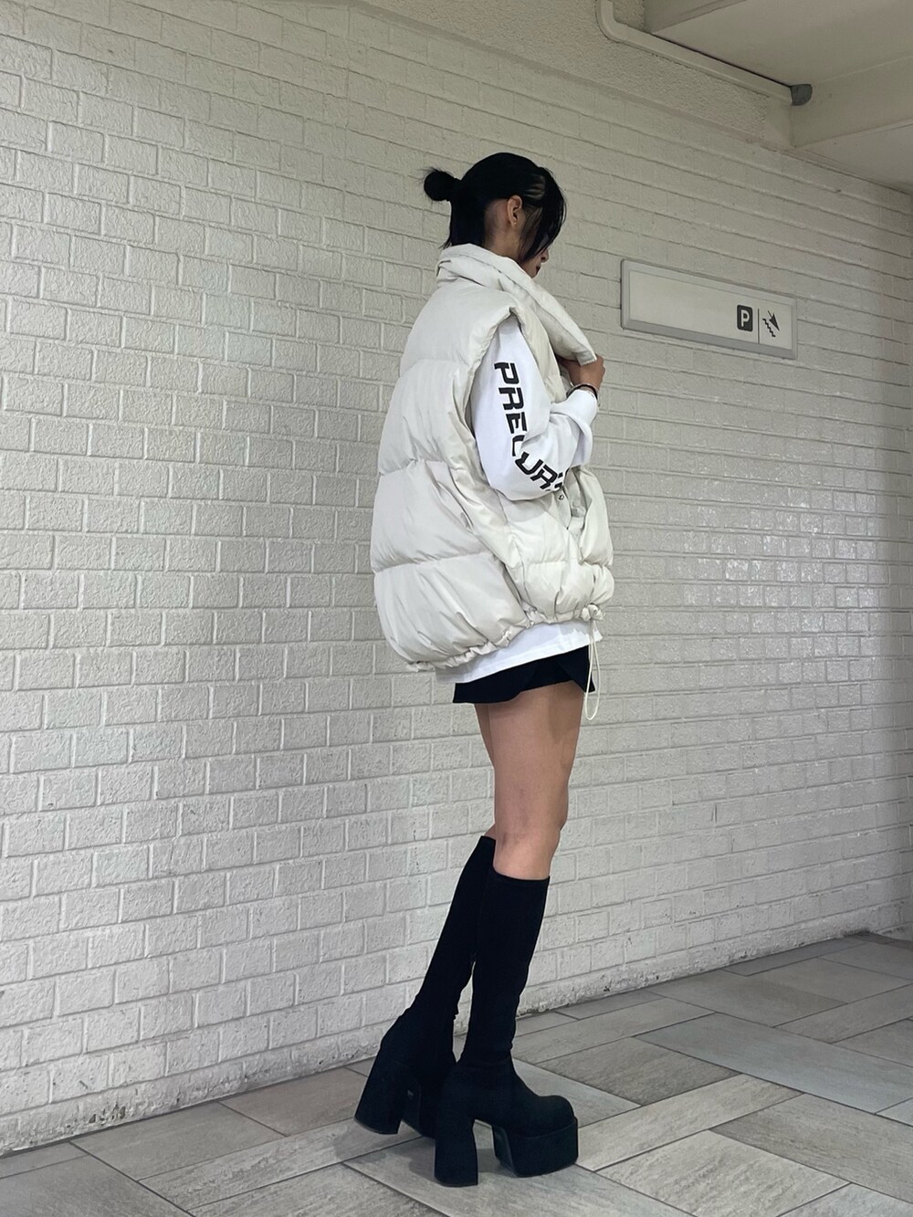 ホワイト系のTシャツ/カットソー、ホワイト系のダウンベスト、ブラック系のスカートを着用したレディースの秋コーディネートの2枚目の写真