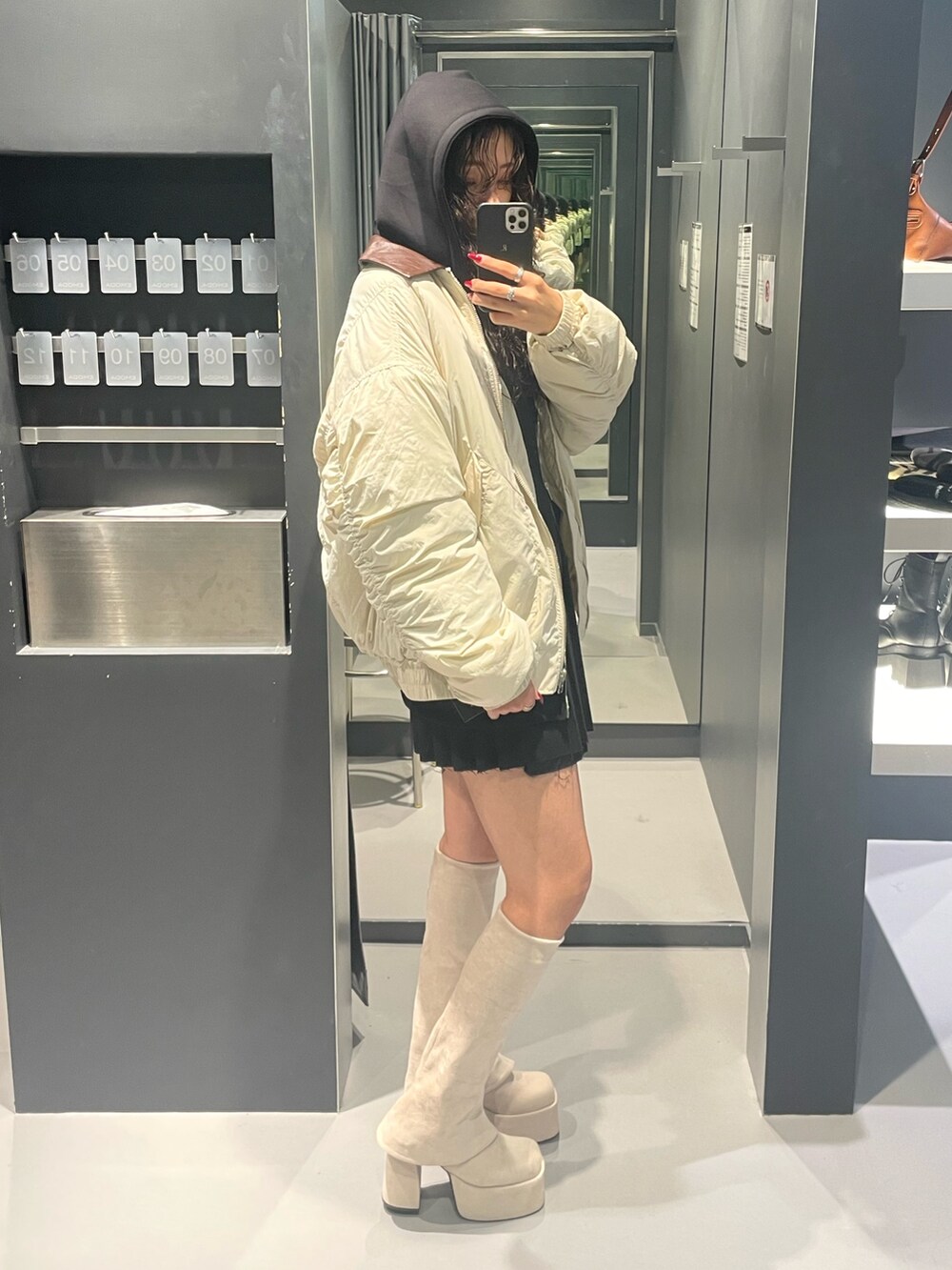 ブラック系のパーカー、ホワイト系のブルゾン、ブラック系のスカートを着用したレディースの秋コーディネートの2枚目の写真