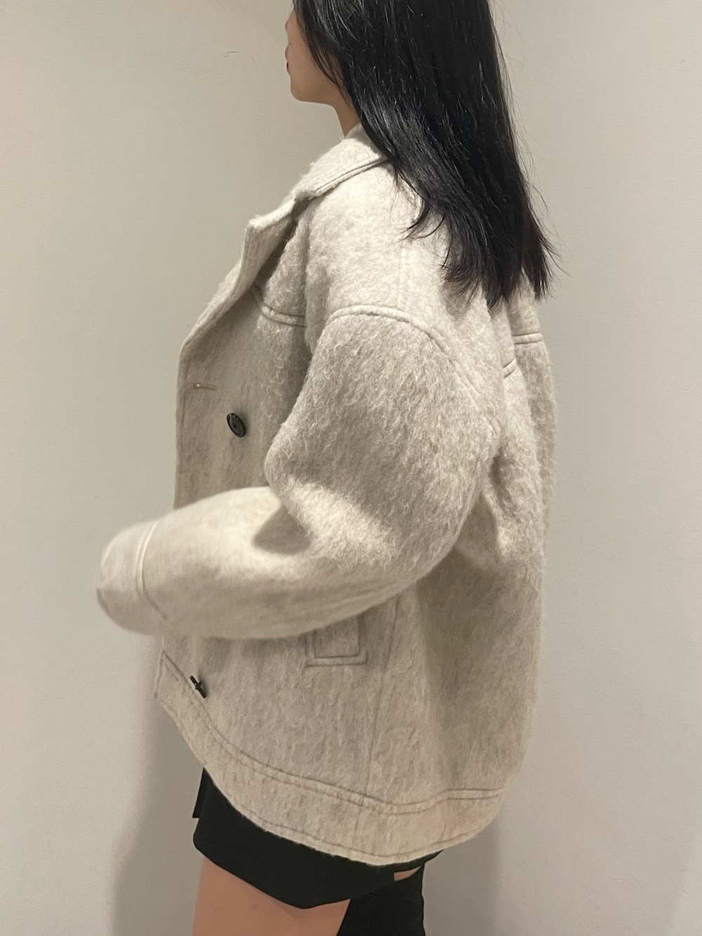 ホワイト系のニット/セーター、ホワイト系のピーコート、ブラック系のスカートを着用したレディースの冬コーディネートの5枚目の写真