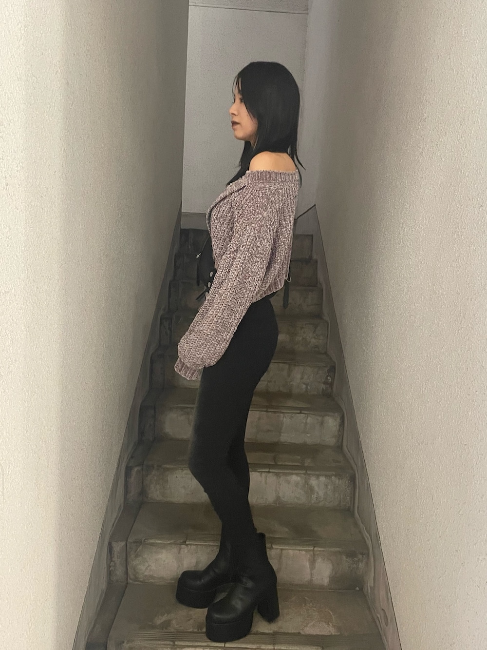 グレー系のニット/セーター、ブラック系のハンドバッグ、ブラック系のデニムパンツを着用したレディースの冬コーディネートの2枚目の写真