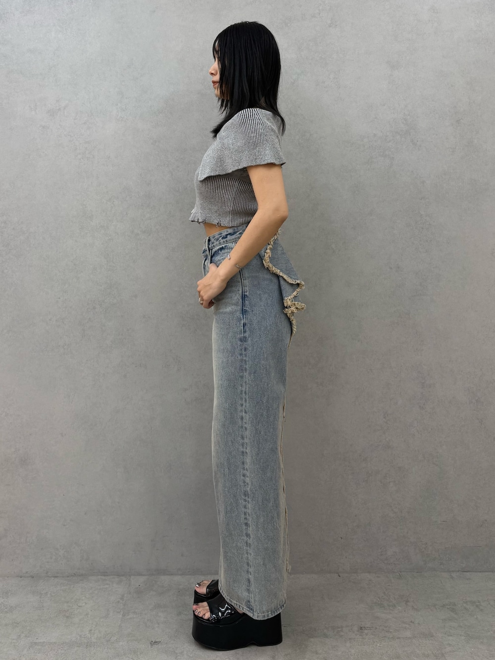 グレー系のニット/セーター、ブルー系のデニムパンツ、ブラック系のサンダルを着用したレディースの春コーディネートの2枚目の写真