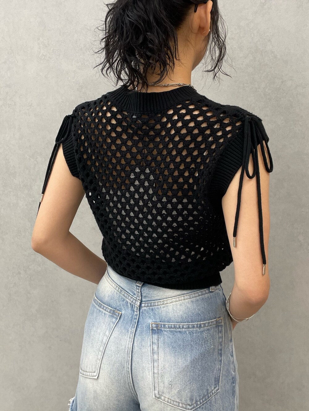 ブラック系のタンクトップ、ホワイト系のキャミソール、ブルー系のデニムパンツを着用したレディースの春コーディネートの6枚目の写真