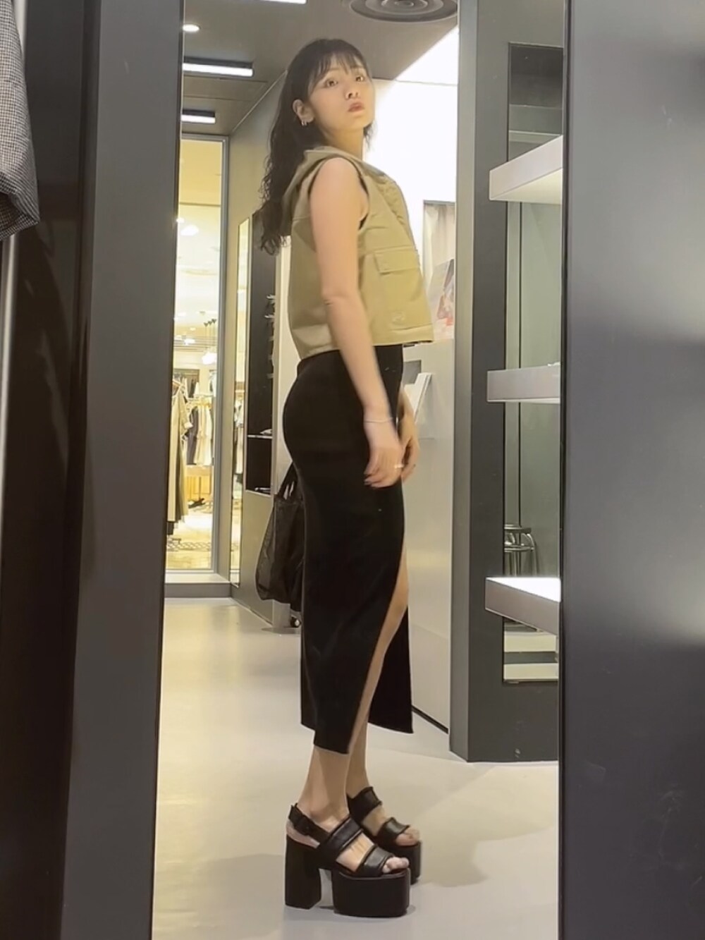 ベージュ系のベスト、ブラック系のワンピース、ブラック系のサンダルを着用したレディースの夏コーディネートの2枚目の写真