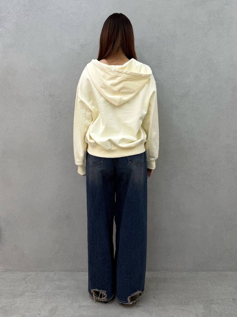 ホワイト系のパーカー、ブルー系のデニムパンツ、ブラック系のパンプスを着用したレディースの冬コーディネートの3枚目の写真