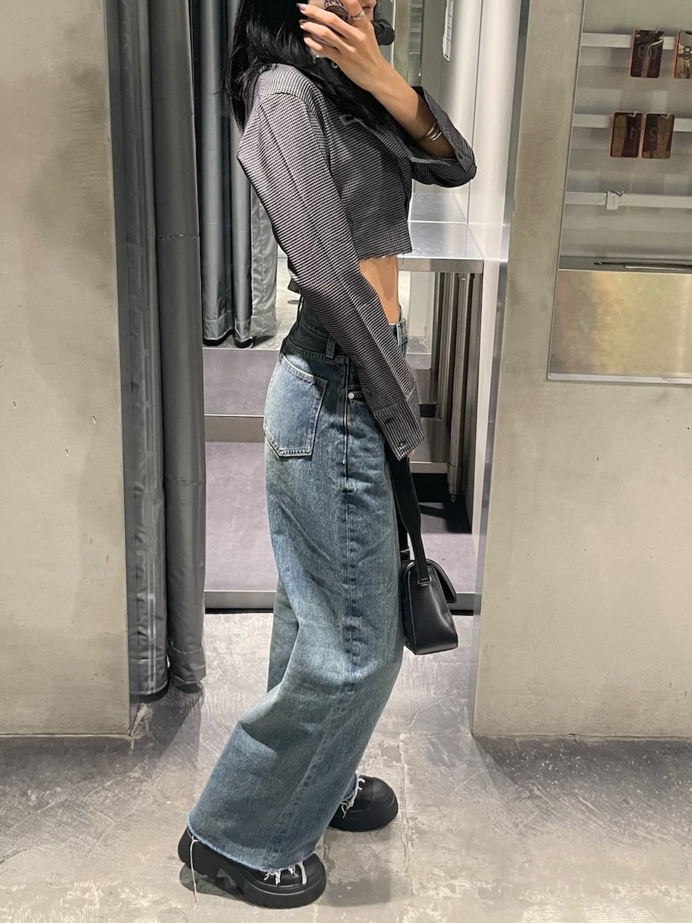 ブルー系のデニムパンツ、ブラック系のブーツ、ブラック系のハンドバッグを着用したレディースの秋コーディネートの8枚目の写真