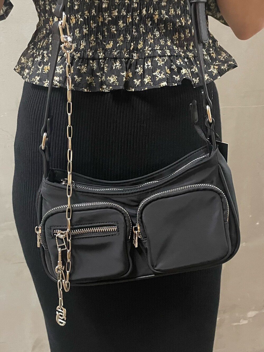 ブラック系のハンドバッグ、ブラック系のスカート、ブラック系のブーツを着用したレディースの秋コーディネートの5枚目の写真