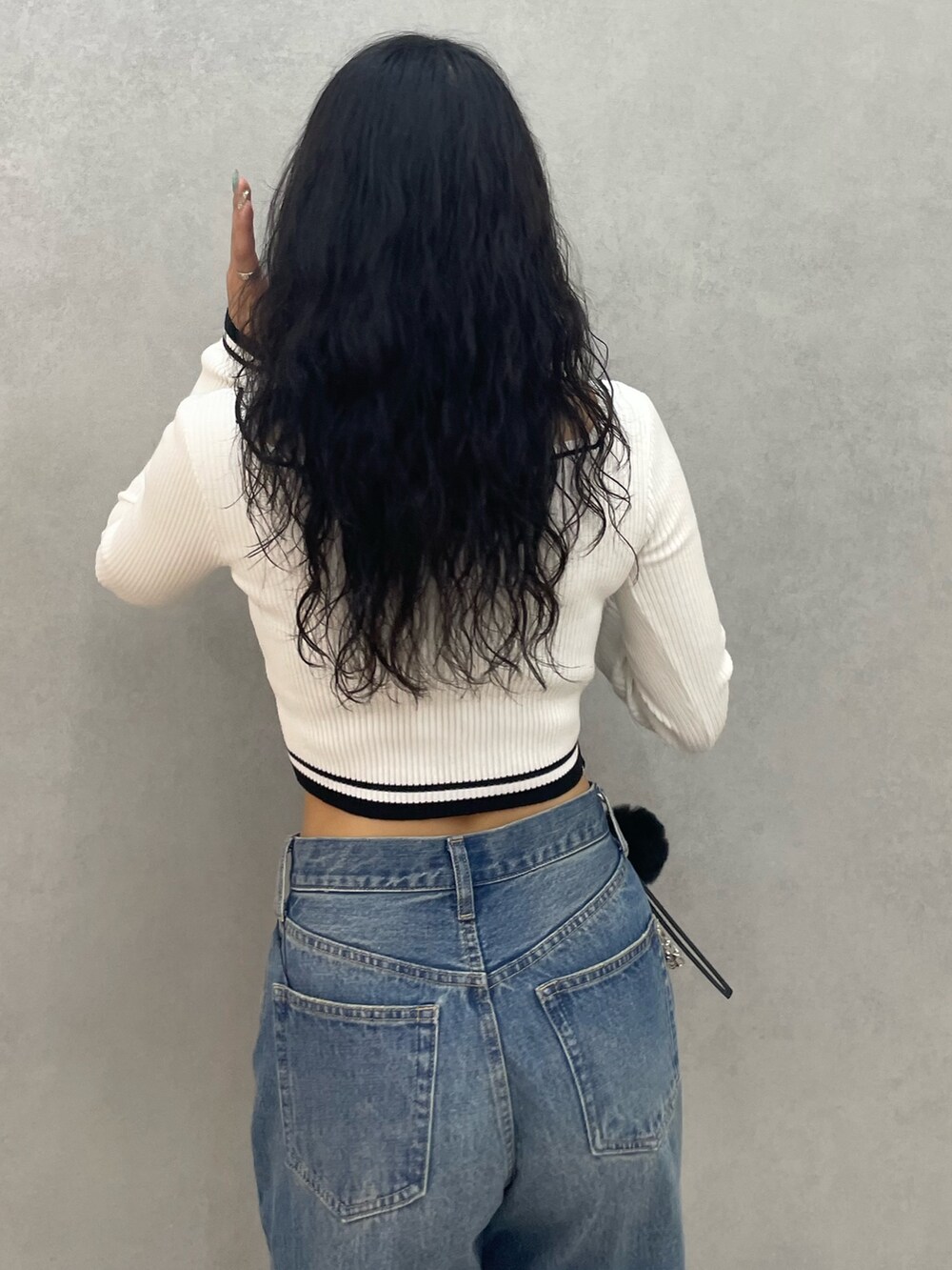 ホワイト系のニット/セーター、ブルー系のデニムパンツ、ブラック系のショルダーバッグを着用したレディースの夏コーディネートの6枚目の写真