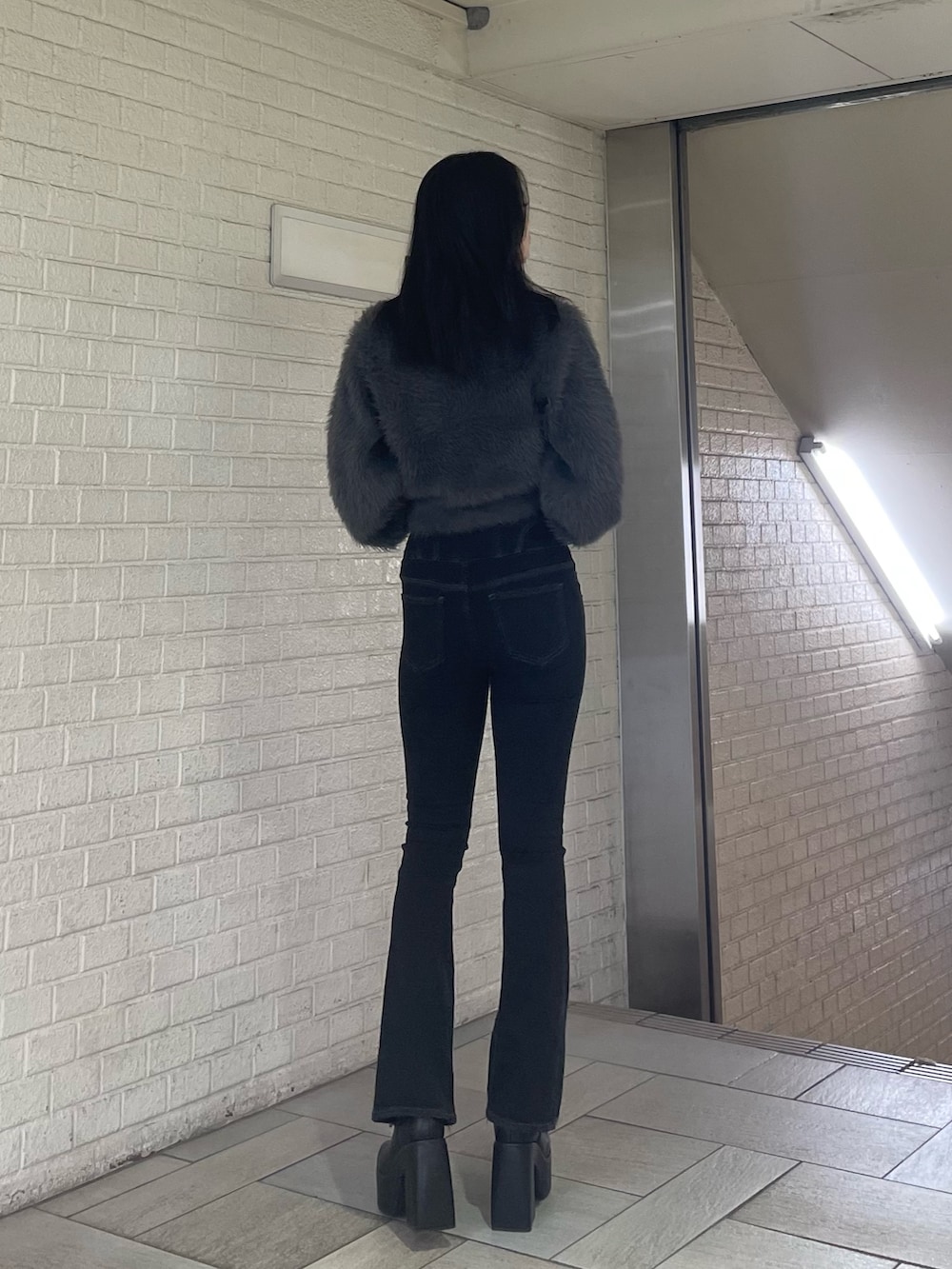 グレー系のニット/セーター、ブラック系のデニムパンツ、ブラック系のブーツを着用したレディースの冬コーディネートの3枚目の写真