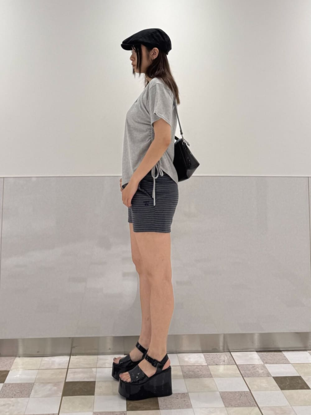 グレー系のTシャツ/カットソー、ブラック系のサンダル、ブラック系のハンドバッグを着用したレディースの夏コーディネートの2枚目の写真