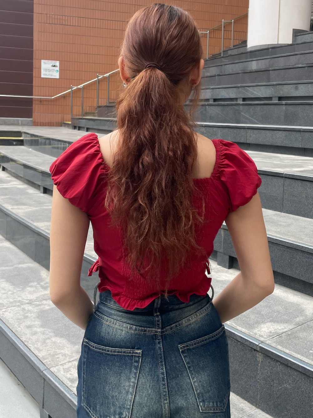 レッド系のTシャツ/カットソー、ブルー系のデニムパンツ、ブラック系のハンドバッグを着用したレディースの春コーディネートの6枚目の写真