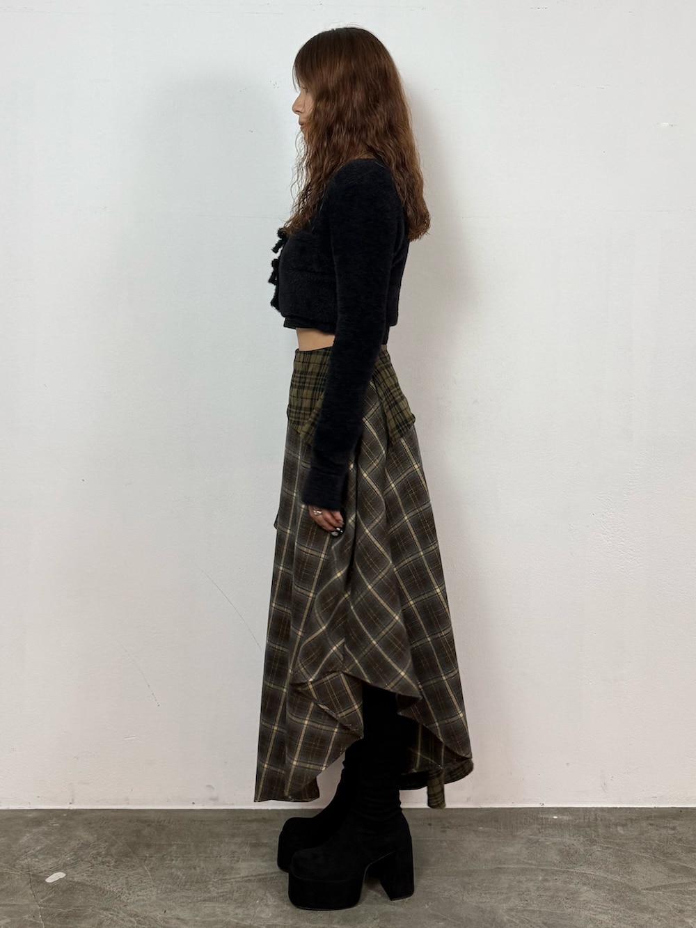 ブラック系のニット/セーター、グリーン系のスカート、ブラック系のブーツを着用したレディースの秋コーディネートの2枚目の写真