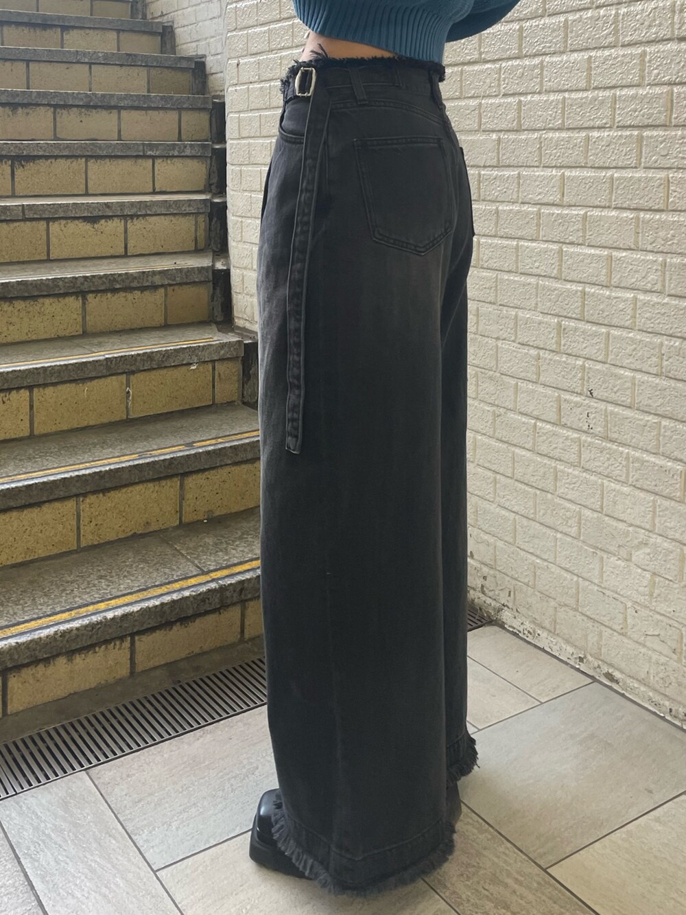 ブルー系のニット/セーター、ブラック系のデニムパンツ、ブラック系のブーツを着用したレディースの春コーディネートの8枚目の写真