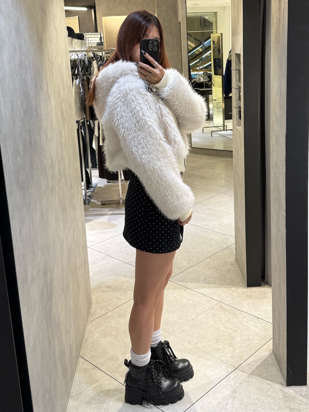 ホワイト系のブルゾン、ブラック系のニット/セーター、ブルー系のスカートを着用したレディースの秋コーディネートの2枚目の写真