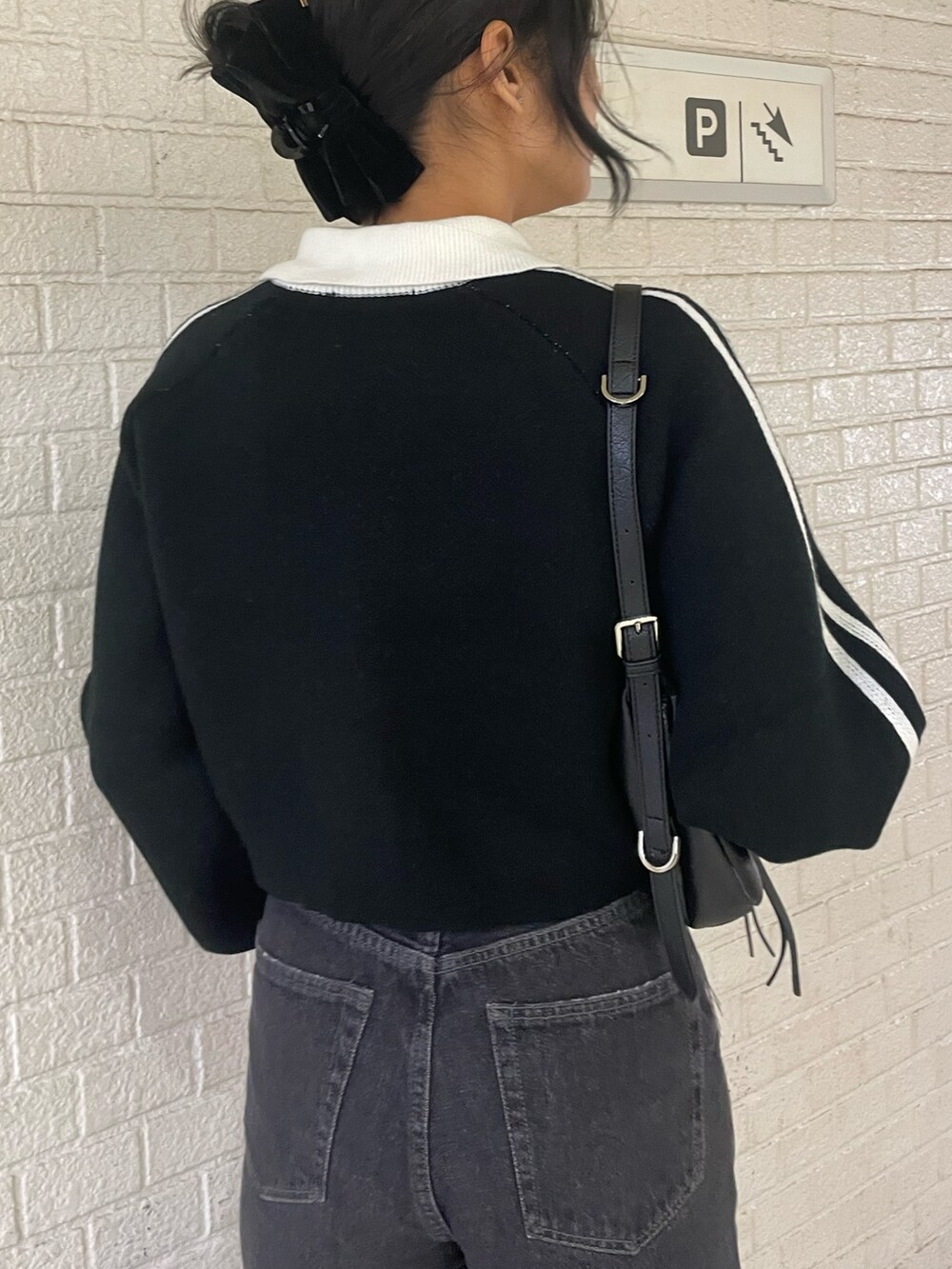 ブラック系のニット/セーター、ブラック系のハンドバッグ、ブラック系のデニムパンツを着用したレディースの冬コーディネートの6枚目の写真