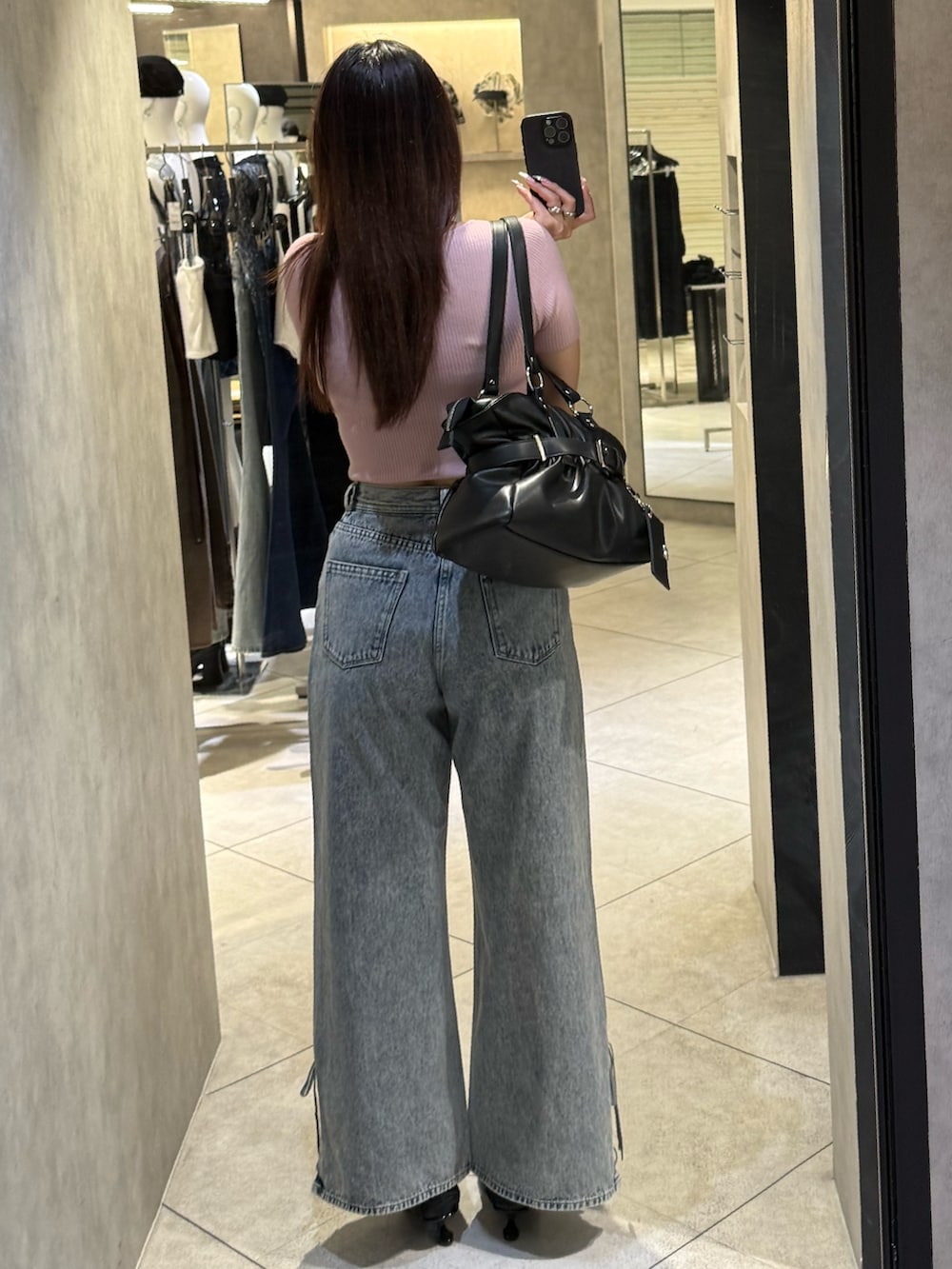 ピンク系のニット/セーター、ブラック系のトートバッグ、ブルー系のデニムパンツを着用したレディースの春コーディネートの3枚目の写真