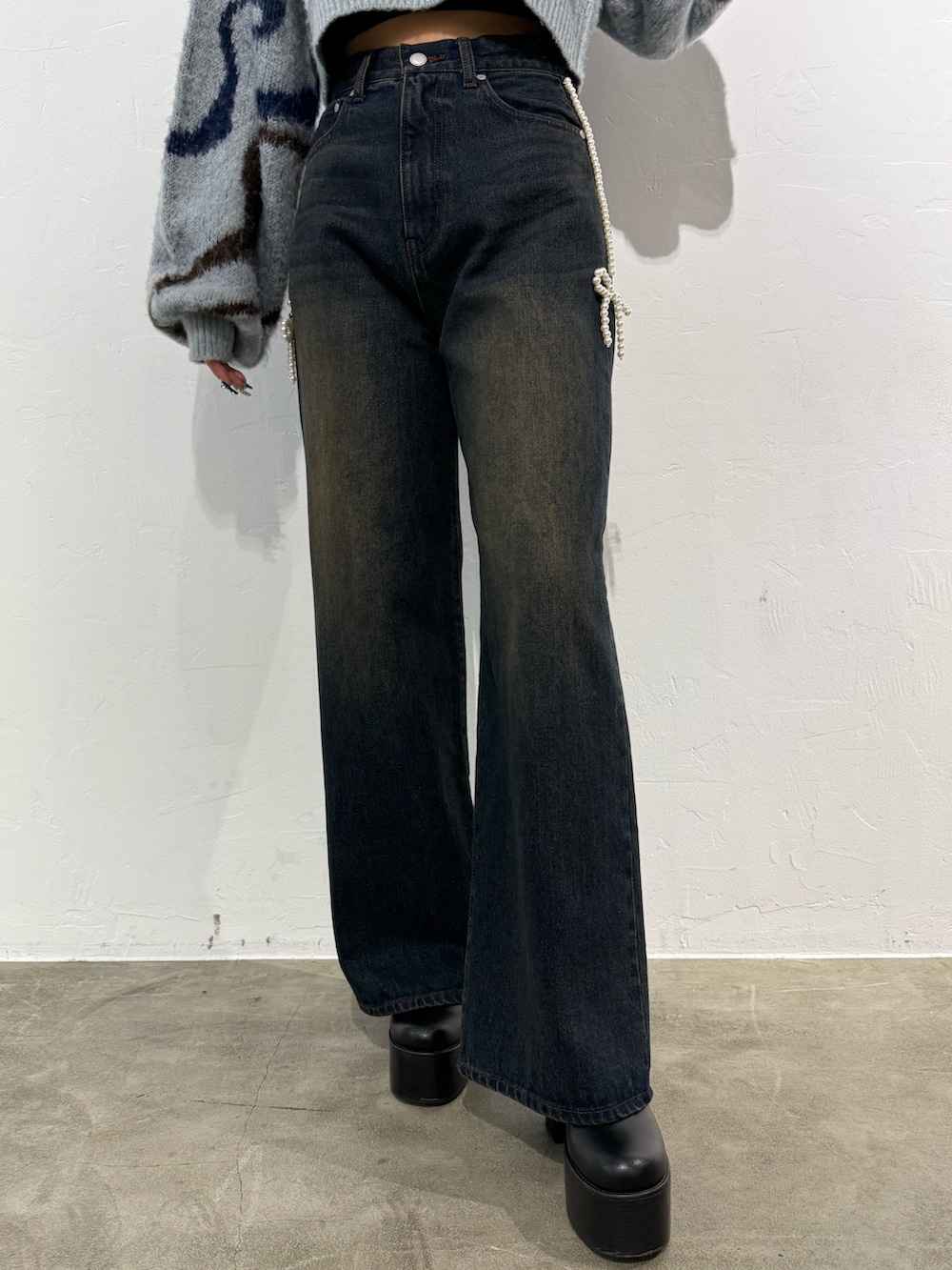 ホワイト系のニット/セーター、ブラック系のブルゾン、ブルー系のデニムパンツを着用したレディースの秋コーディネートの6枚目の写真