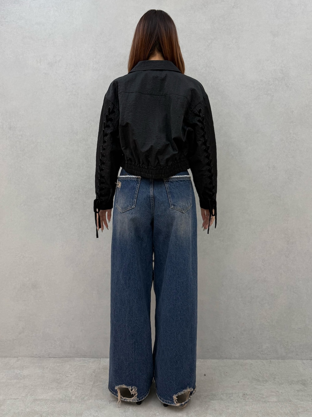 ブラック系のブルゾン、ホワイト系のニット/セーター、ブルー系のデニムパンツを着用したレディースの冬コーディネートの3枚目の写真