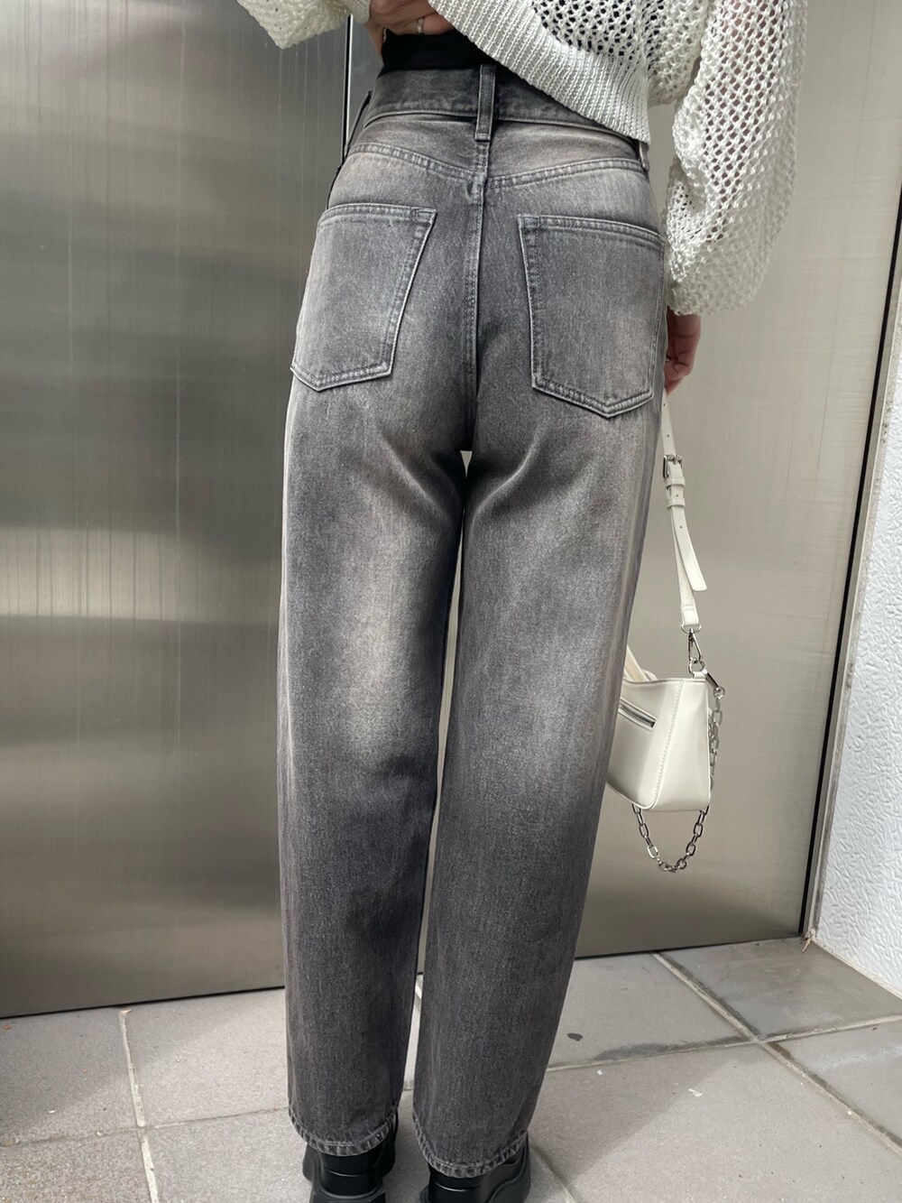 ホワイト系のニット/セーター、ブラック系のキャミソール、グレー系のデニムパンツを着用したレディースの春コーディネートの8枚目の写真