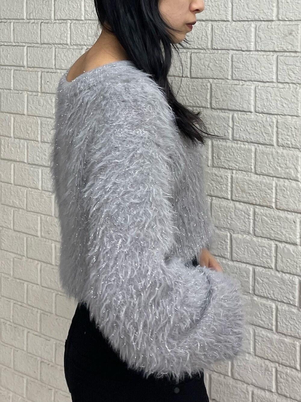 グレー系のニット/セーター、ブラック系のデニムパンツ、ブラック系のブーツを着用したレディースの冬コーディネートの5枚目の写真