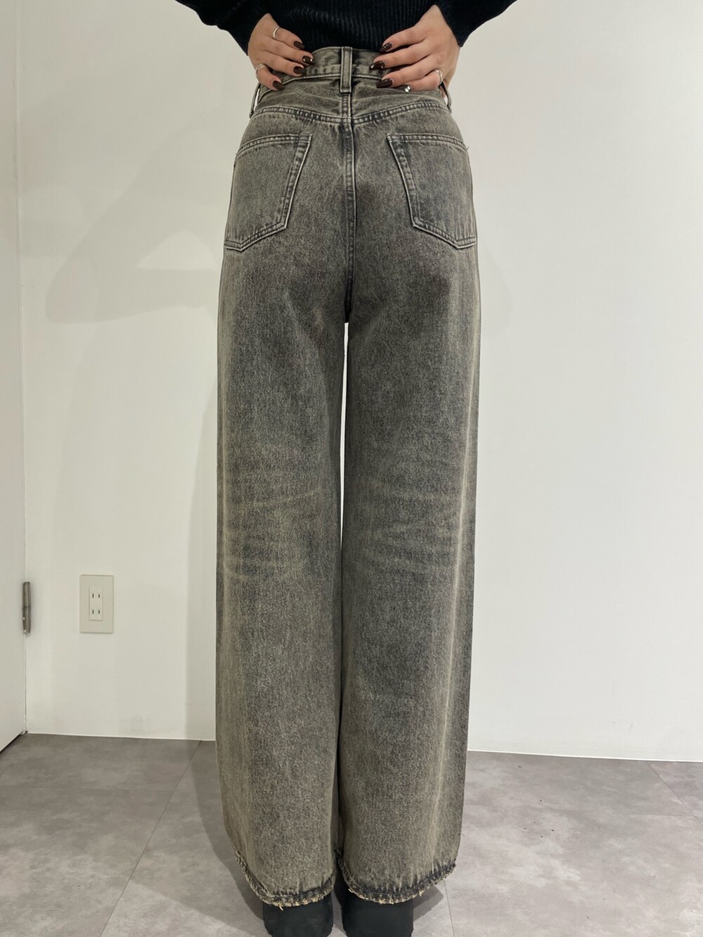 ブラック系のニット/セーター、グレー系のデニムパンツ、ブラック系のブーツを着用したレディースの春コーディネートの9枚目の写真