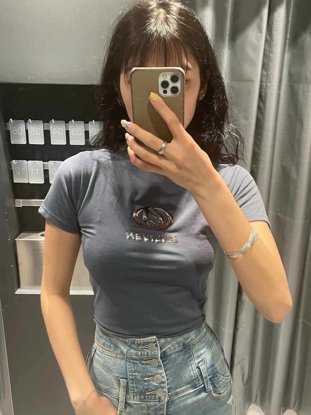 グレー系のTシャツ/カットソー、ブラック系のデニムスカート、ブラック系のショルダーバッグを着用したレディースの春コーディネートの4枚目の写真