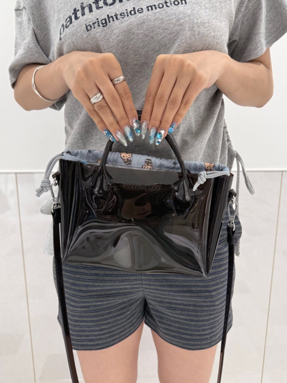 グレー系のTシャツ/カットソー、ブラック系のサンダル、ブラック系のハンドバッグを着用したレディースの夏コーディネートの6枚目の写真