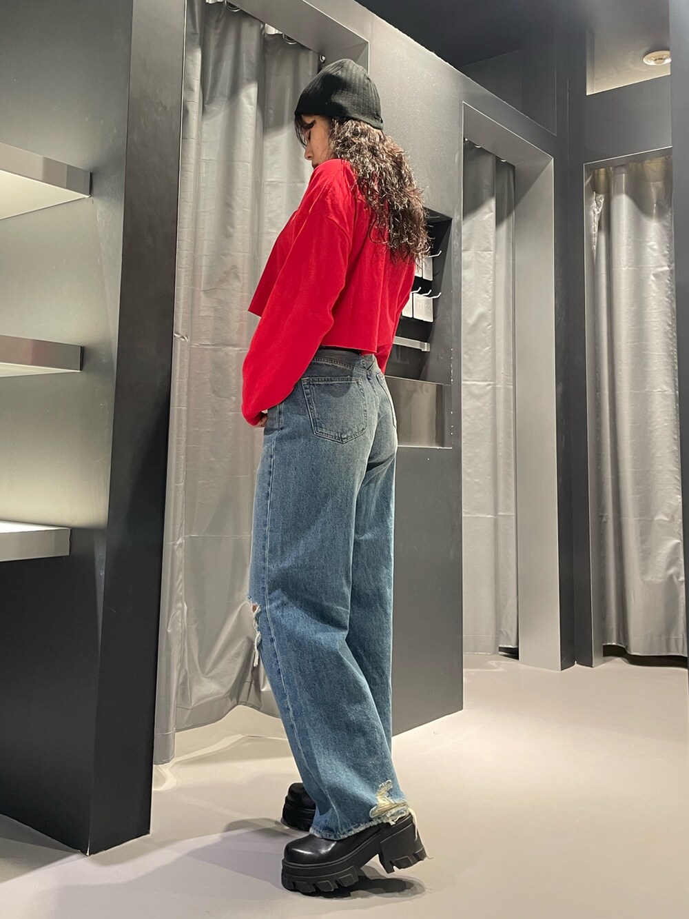 レッド系のTシャツ/カットソー、ブルー系のデニムパンツ、ブラック系のブーツを着用したレディースの秋コーディネートの2枚目の写真