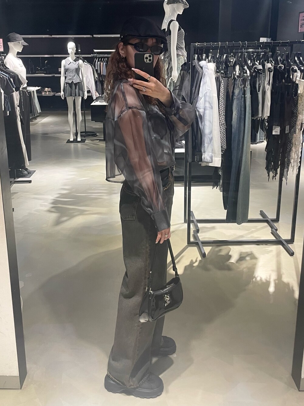 グレー系のニット/セーター、ブルー系のシャツ/ブラウス、ブルー系のデニムパンツを着用したレディースの春コーディネートの2枚目の写真